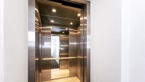 Un ascenseur aux parois métalliques et dont le plancher est éclairé.