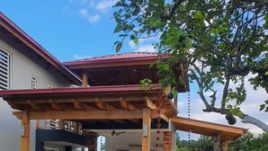 A house with a covered patio, a garden with bougainvillea, and a tree with fruit.