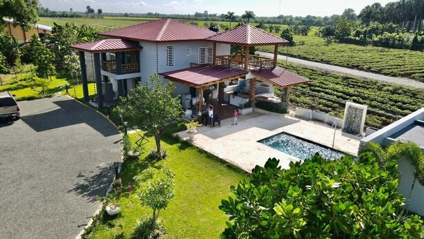 A two-story house with a covered patio and a swimming pool.