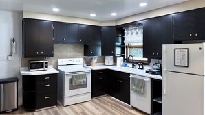 A modern kitchen with dark cabinets, a white refrigerator, and a stainless steel oven. - The Huddle - Near Lambeau Field/Resch Center (Green Bay)