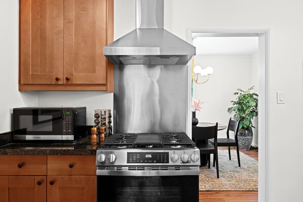 A kitchen with a stainless steel range hood, a microwave, and a gas stove.