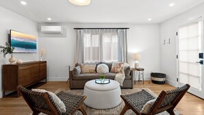 Una sala de estar moderna con un sofá, un reposapiés y dos sillones de mimbre.