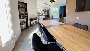 A modern kitchen with a wooden dining table, black chairs, and pendant lighting.