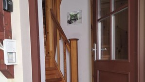 Unes escales de fusta que porten a una porta amb un panell de vidre.