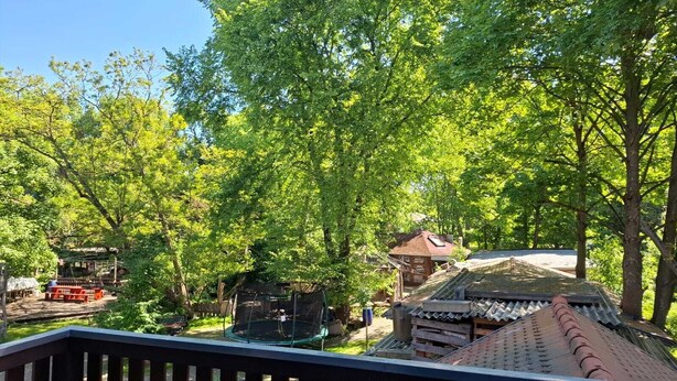 Un edifici tradicional japonès amb teulada d'aquarelles, envoltat d'arbres verds i frondosos.