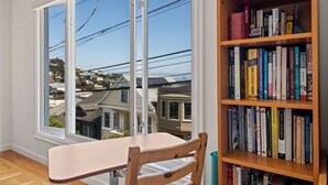 Une pièce avec une grande fenêtre, une bibliothèque en bois et une petite table.