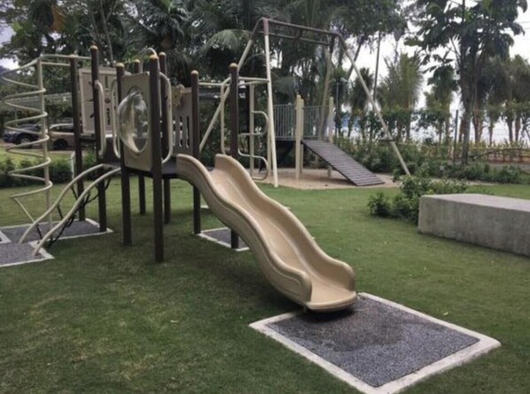 Ein Spielplatz mit Rutsche, Klettergerüsten und einer kleinen Anhöhe.