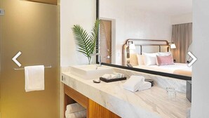 Een moderne badkamer met een grote spiegel, een wastafel en een douchegedeelte.
