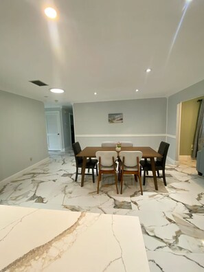 A dining area with a marble floor, a wooden table, and four chairs. - Peaceful and newly home with solar heated pool (Brandon)