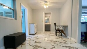 A hallway with a marble floor, a ceiling fan, a bench, and a door leading to another room. - Peaceful and newly home with solar heated pool (Brandon)