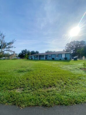 A single-story house with a blue exterior, a front yard, and a clear sky. - Peaceful and newly home with solar heated pool (Brandon)