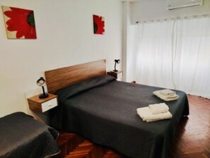 A bedroom with a bed, a bedside table, a lamp, and a window with curtains. - Gran monoambiente en centro de Bs As 1 C (Buenos Aires)