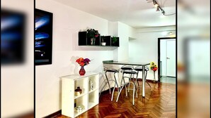 A modern kitchen with a dining area, wooden flooring, and a white cabinet with decorative items. - Gran monoambiente en centro de Bs As 1 C (Buenos Aires)
