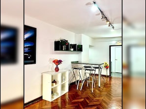A modern kitchen with a dining area, wooden flooring, and a white cabinet with decorative items. - Gran monoambiente en centro de Bs As 1 C (Buenos Aires)