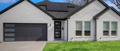 A modern two-story house with a garage, a front door, and a well-maintained lawn.