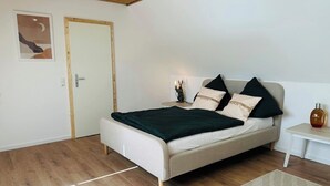 A bedroom with a bed, a nightstand, a lamp, and a bottle of lotion. - Cozy Family Home near Ramstein Air Base – Comfort & Convenience (Hochspeyer)