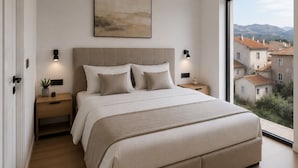 Ein modernes Schlafzimmer mit einem großen Bett, Nachttischen, einer Wandleuchte und Blick auf Gebäude durch ein großes Fenster.