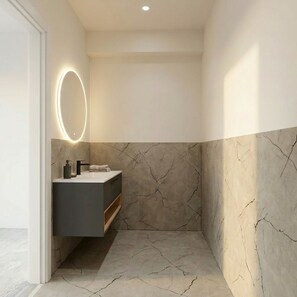Ein modernes Badezimmer mit Marmorwaschtisch, integrierter Dusche und Wandleuchte.