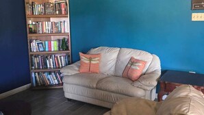 A living room with a beige sofa, a bookshelf, and a blue wall. -  A 3-bedroom house  in Georgetown, close to downtown, fully fenced back yard.  (Georgetown)