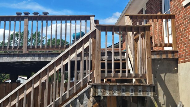 A wooden deck with a railing, a brick building, and a clear blue sky. -  A 3-bedroom house  in Georgetown, close to downtown, fully fenced back yard.  (Georgetown)