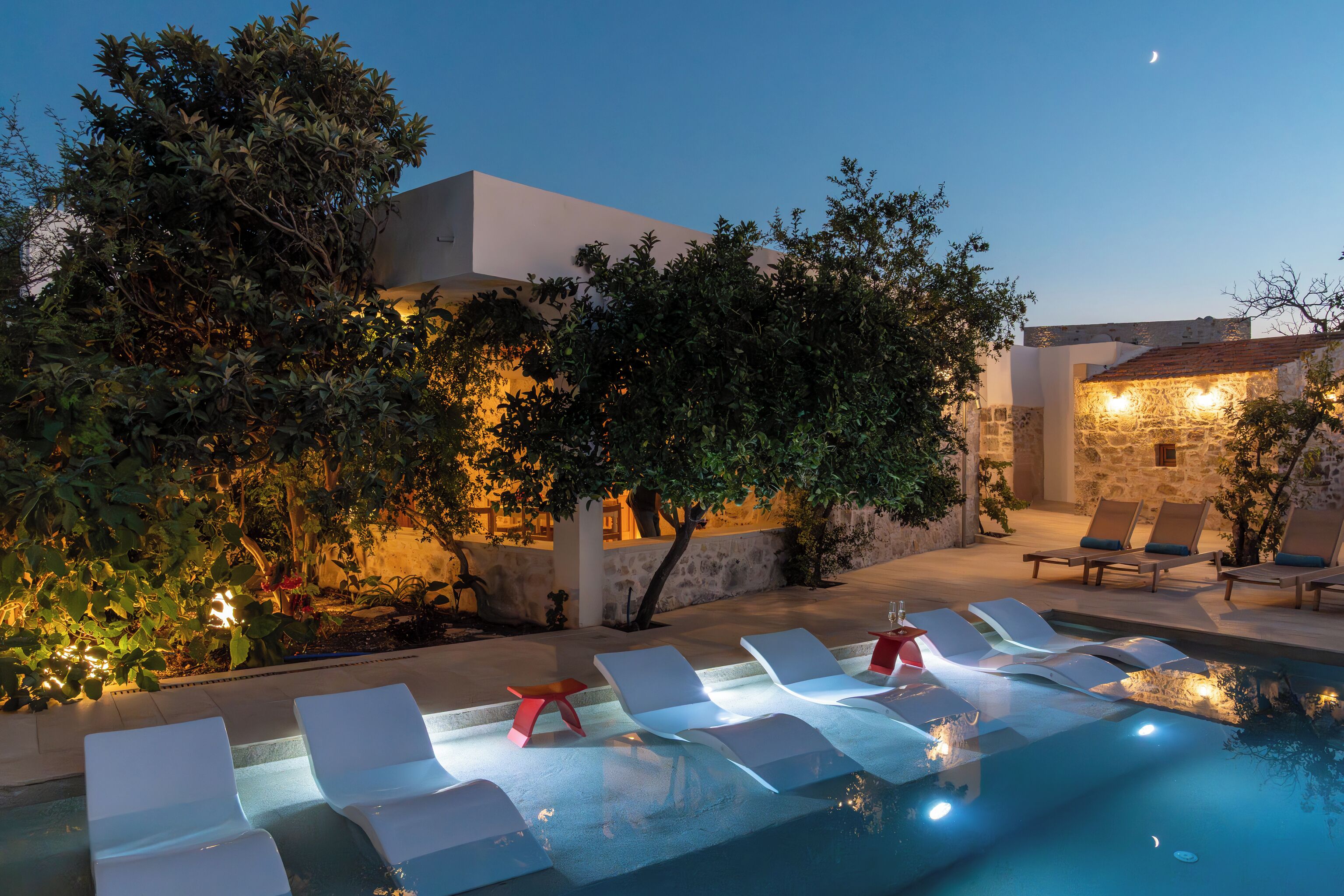 A poolside area with lounge chairs and a stone wall.