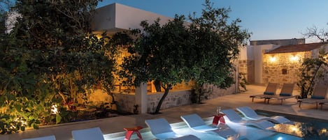 A poolside area with lounge chairs and a stone wall.