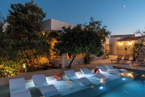 A poolside area with lounge chairs and a stone wall.