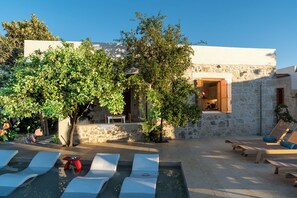 A stone building with a pool area, including sun loungers and a small table.