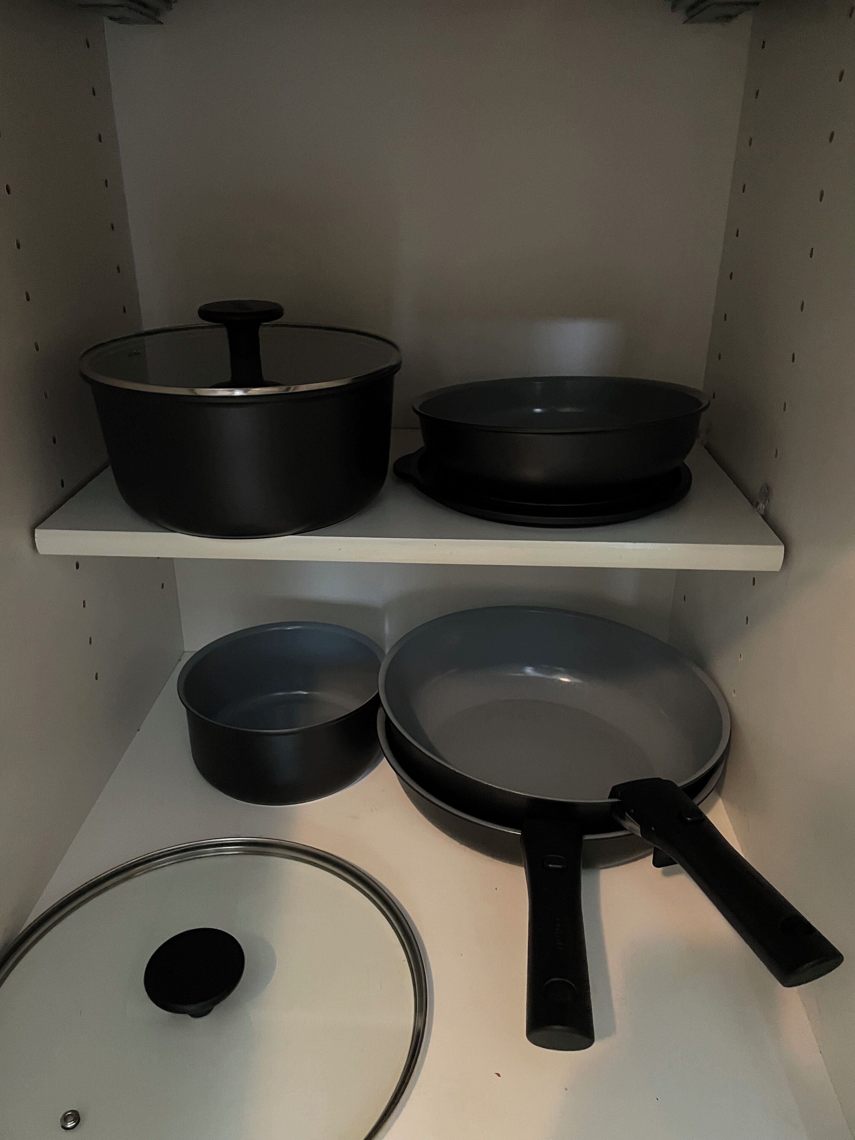 A kitchen with four black cookware items on shelves.