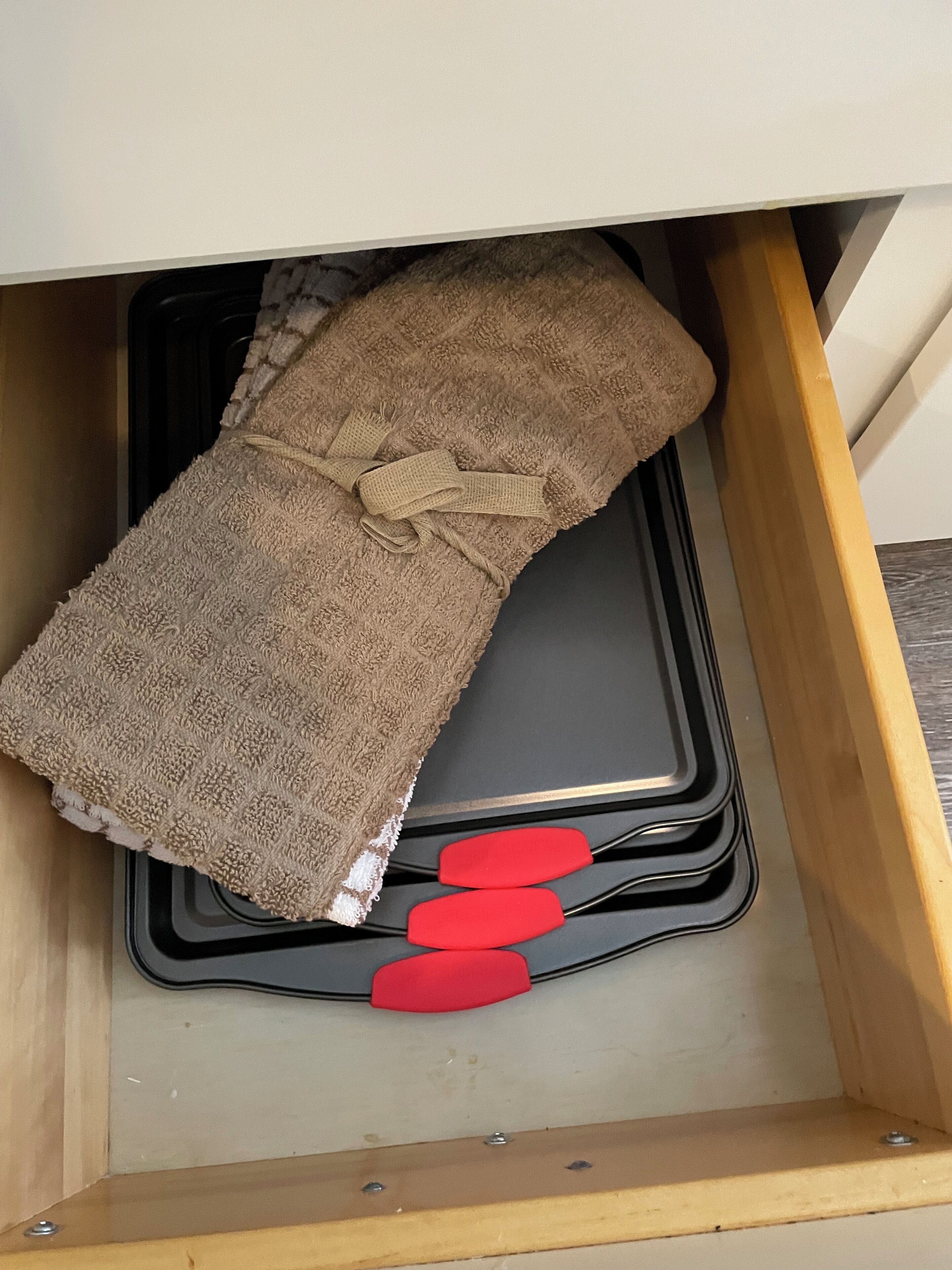 Een lade met een bruine handdoek, een zwarte dienblad en twee rode spatels.