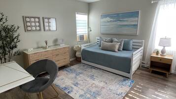A bedroom with a bed, desk, chair, and a ceiling fan.