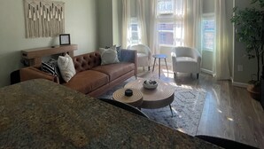A spacious living room with a brown leather sofa, a coffee table, and a ceiling fan.