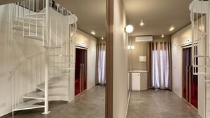 Een ruim interieur met een centrale trap, een keukenhoek en een badkamer.