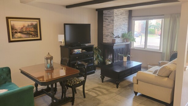 Una sala de estar con televisión, chimenea, mesa de comedor con sillas y sofá.
