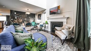 A modern living room with a sofa, armchairs, a fireplace, and a television. - 5BD Jungle Oasis - Hot Tub - BBQ - King Bed - Games - AC (Edmonton)