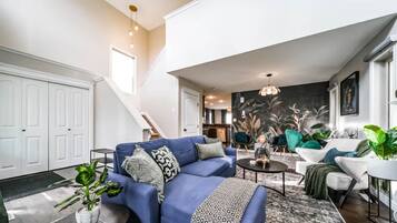 A modern living room with a blue sofa, a coffee table, and a staircase leading to another level.