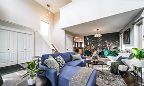 Ein modernes Wohnzimmer mit einem blauen Sofa, einem Couchtisch und einer Treppe, die zu einer anderen Ebene führt.