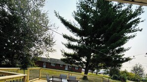 Une terrasse en bois avec une table et des chaises, entourée d’une rambarde.