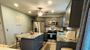 Une cuisine moderne avec des meubles de couleur sombre, des appareils électroménagers en acier inoxydable et un îlot central en bois.