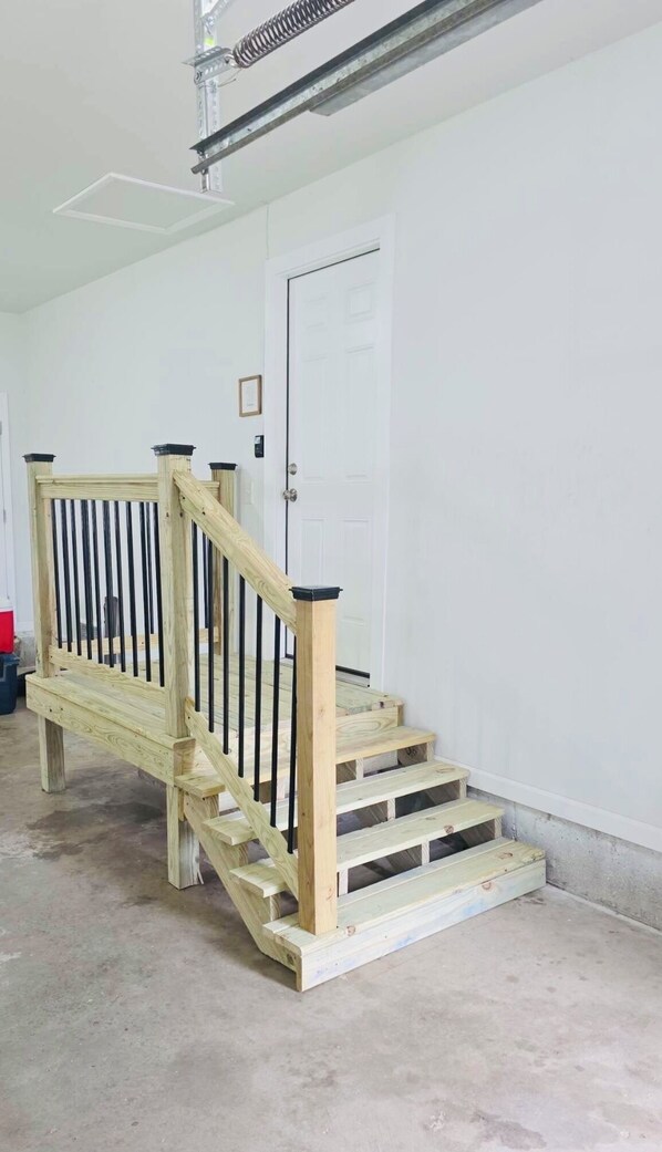 Eine Holztreppe mit schwarzen Geländern, die zu einer weißen Tür führt.