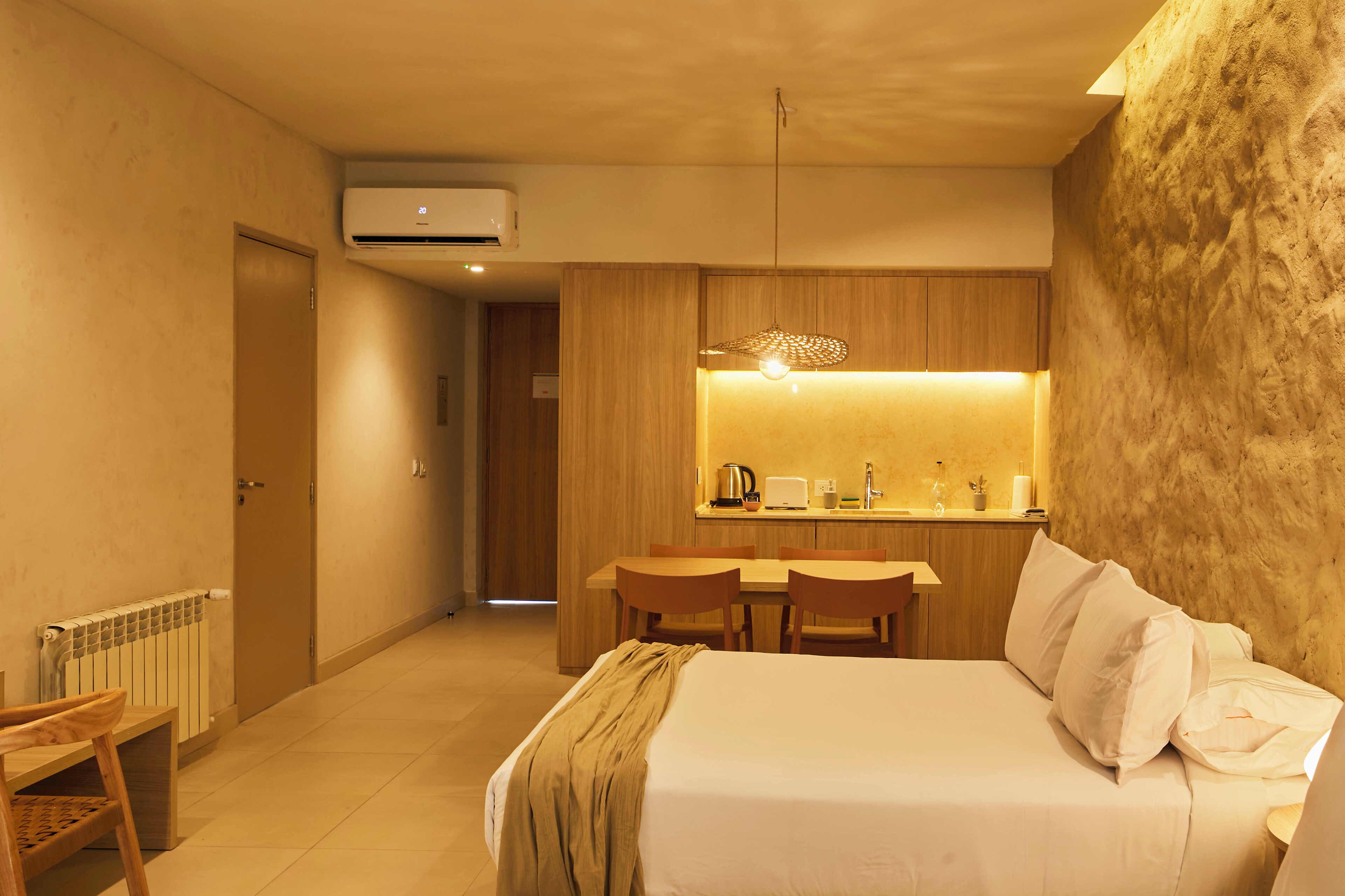 A hotel room with a bed, a desk, and a kitchenette.