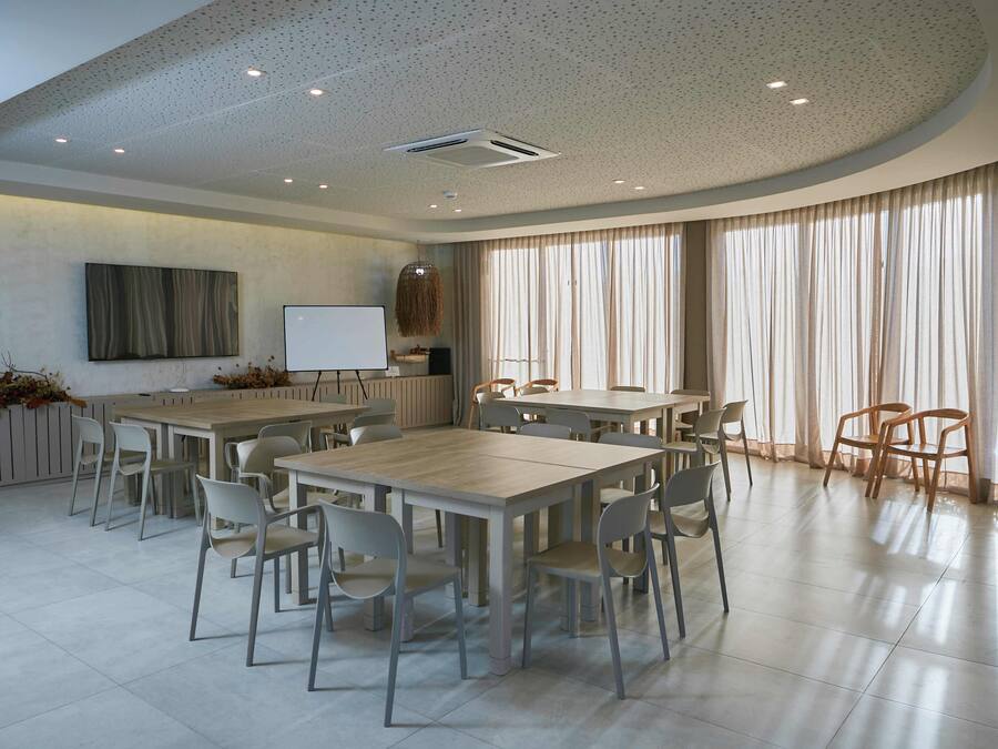 A spacious conference room with a large table and chairs, a whiteboard, and a large window with curtains.