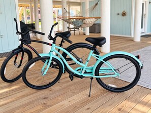 Two bicycles parked indoors with a hammock and a door in the background.