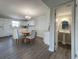 A modern kitchen with white cabinets, a dining table with chairs, and a chandelier.