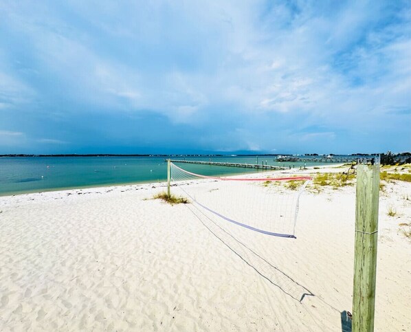 A beach with a volleyball net, clear skies, and a calm sea.
