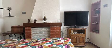 A bedroom with a bed, a fireplace, a television, and a wooden ceiling.