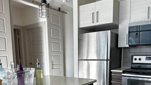 Een moderne keuken met een wijnkoeler, roestvrijstalen apparatuur en een hanglamp.