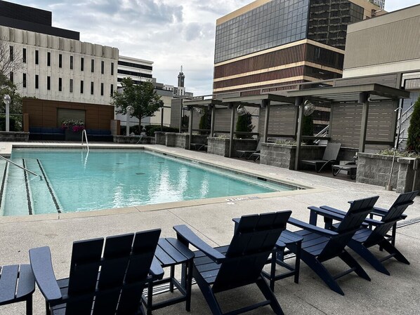 A pool area with lounge chairs and a view of modern buildings.
