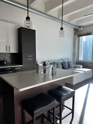 A modern kitchen with a central island, bar stools, and a built-in seating area with cushions.