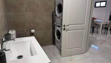 Une salle de bain moderne avec un lavabo blanc, un lave-linge et des toilettes.
